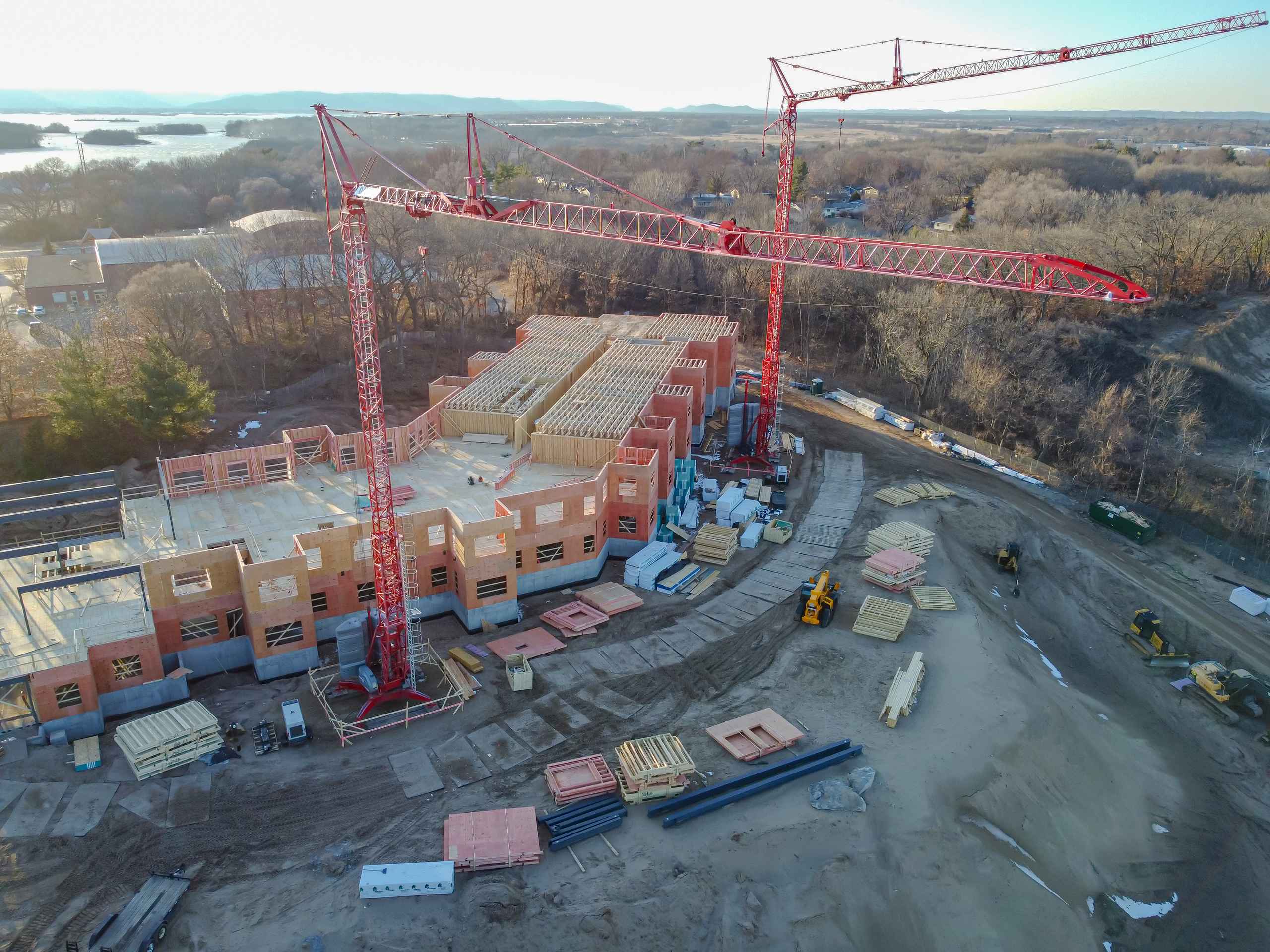 Top-down dusk aerial over a tower crane and laydown yard