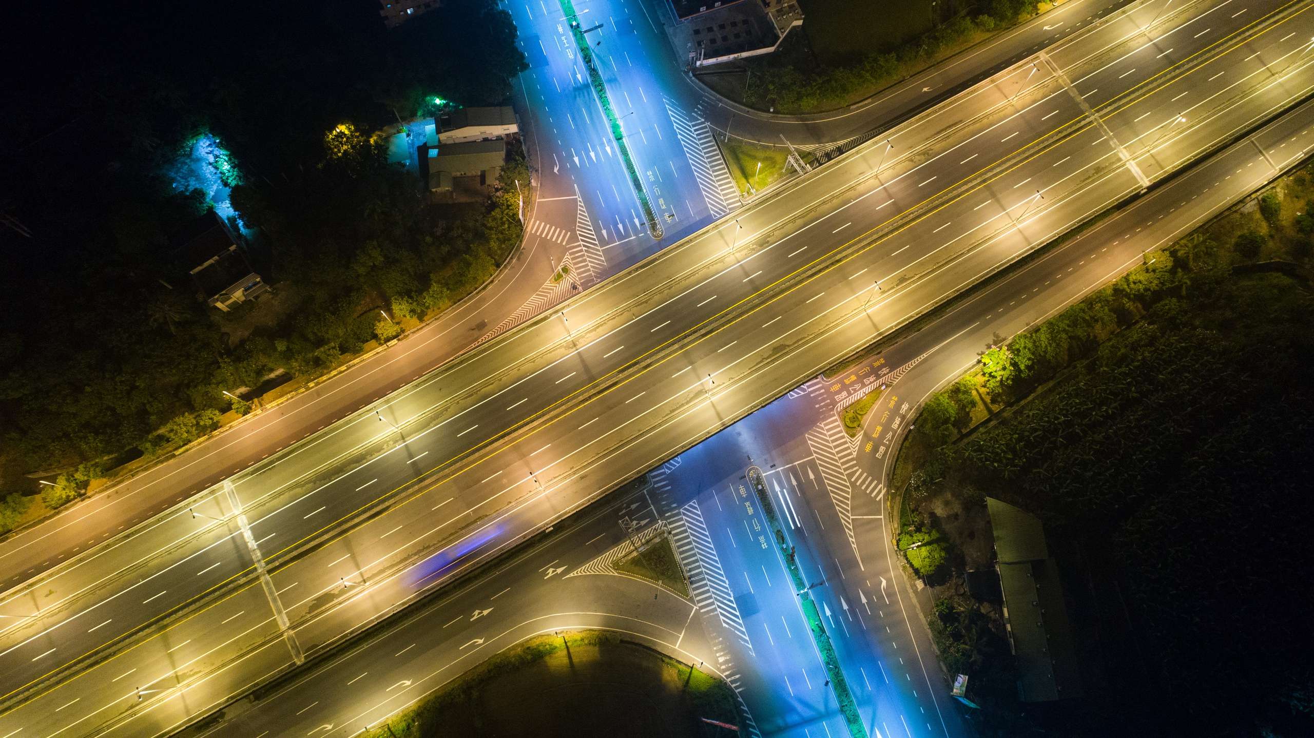 Night highway interchange aerial with light trails